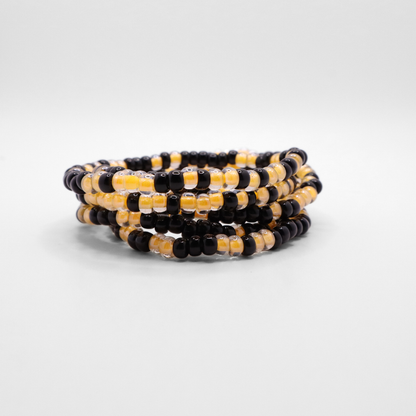 Set of six black and gold seed bead stretch bracelets featuring random black and gold seed beads on a white background