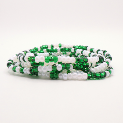 Set of six green and white seed bead stretch bracelets featuring random green and white seed beads on a white background