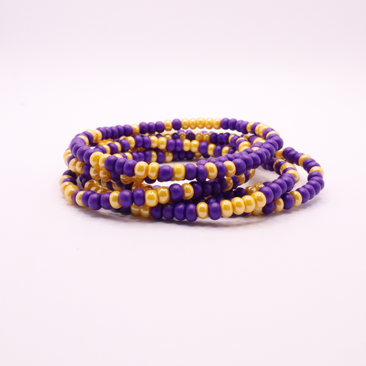 Set of six purple and gold seed bead stretch bracelets featuring random purple and gold seed beads on a white background