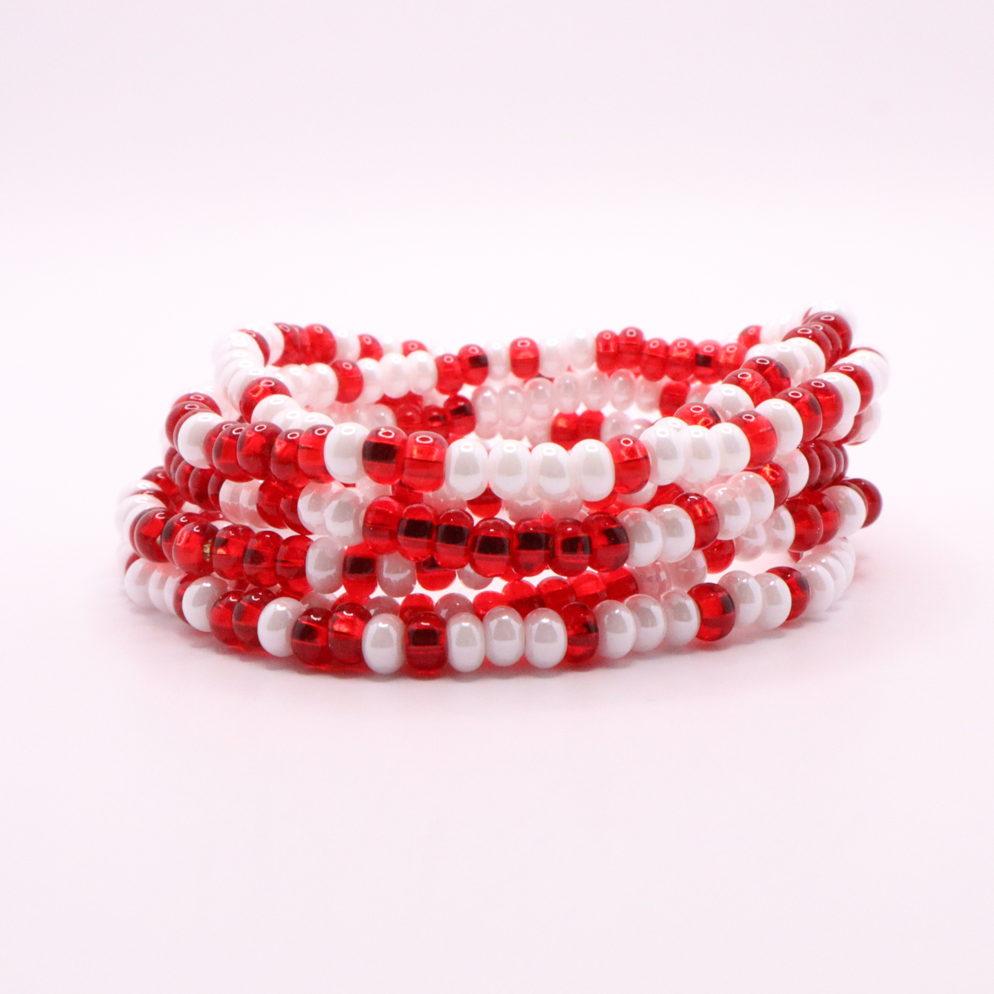 Set of six red and white seed bead stretch bracelets featuring random red and white seed beads on a white background