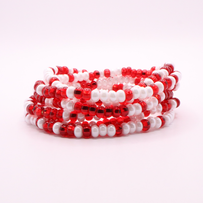 Set of six red and white seed bead stretch bracelets featuring random red and white seed beads on a white background