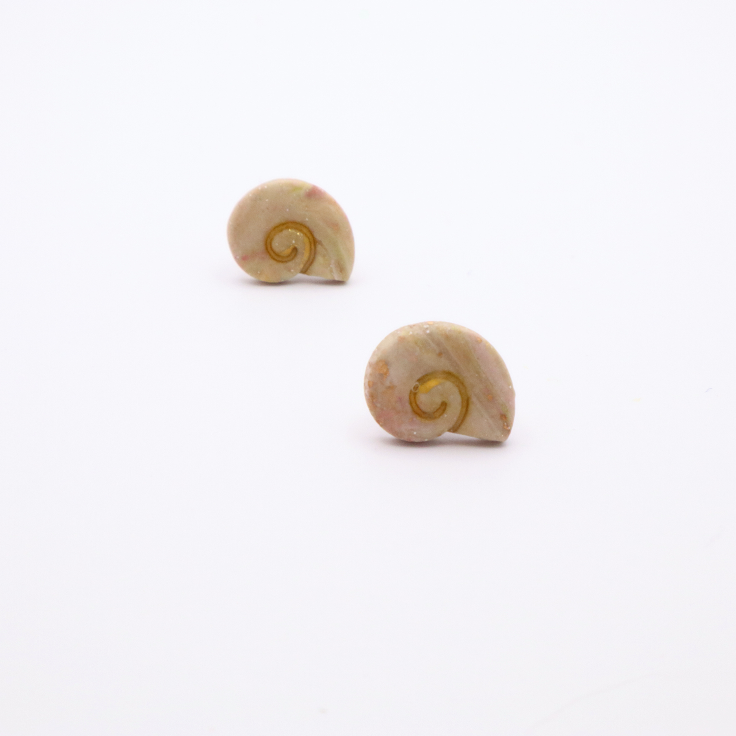 Pair of neutral-toned shell stud earrings with gold swirl design photographed individually