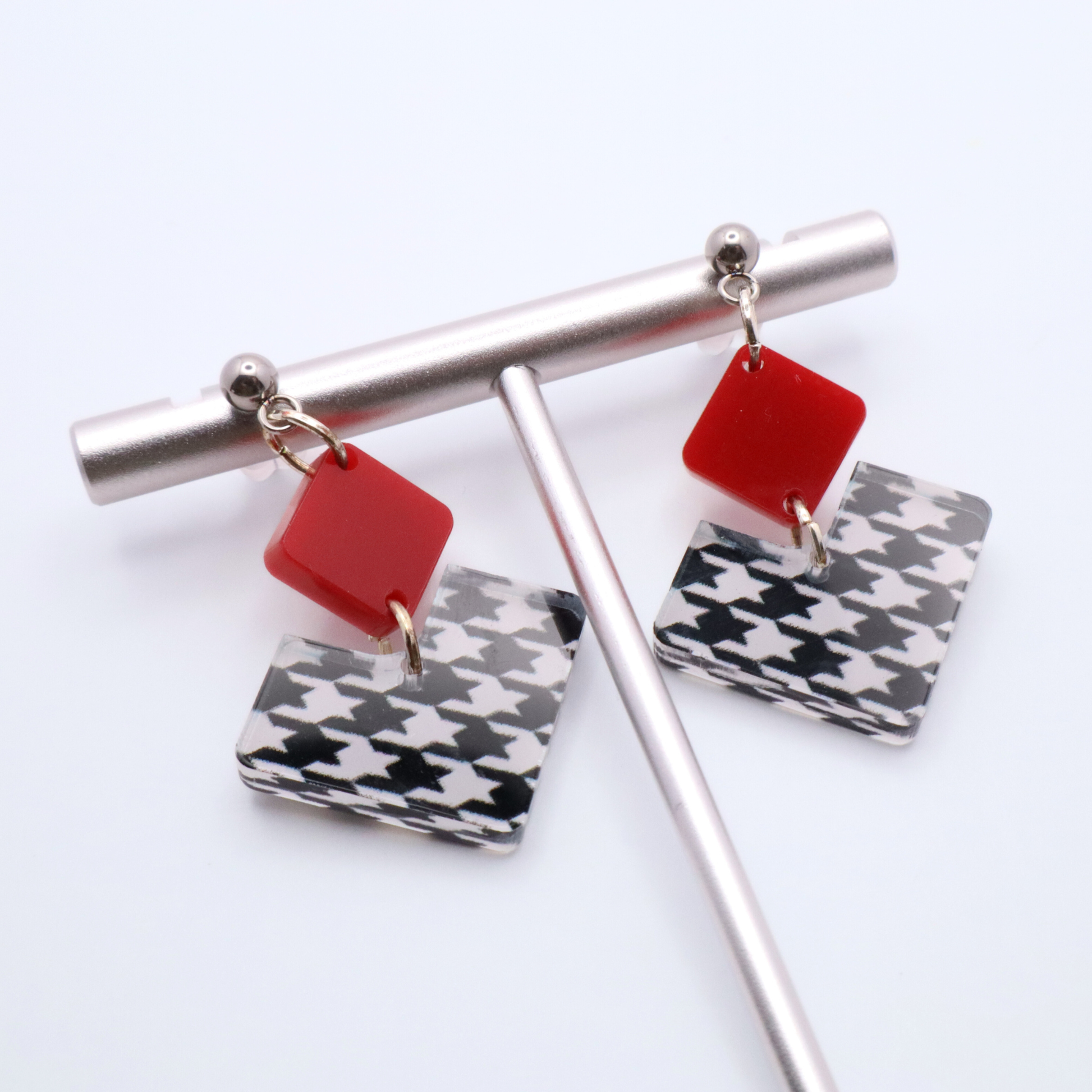Earrings with red and houndstooth patterned charms on a white background