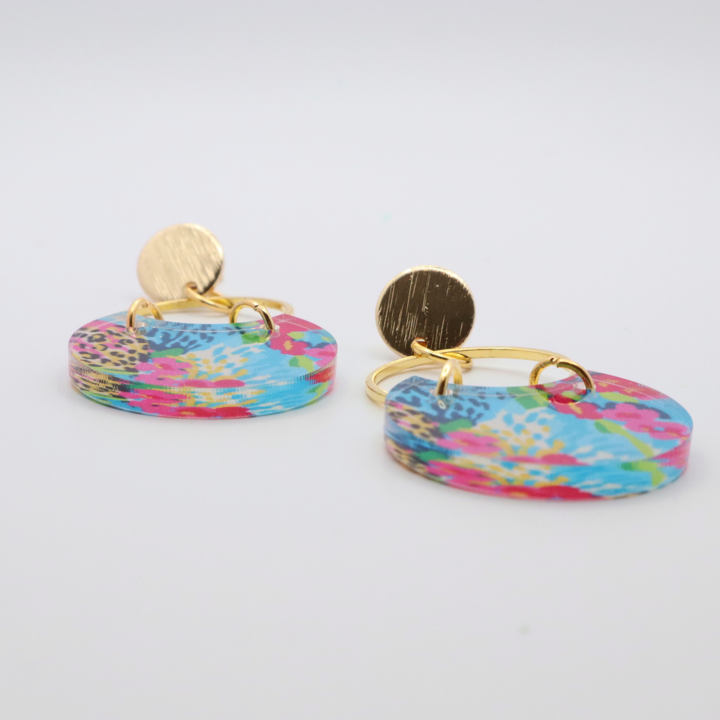 Side view of acrylic dangle earrings showing thickness and glossy finish with colorful floral print and gold hoop with 18k gold plated posts
