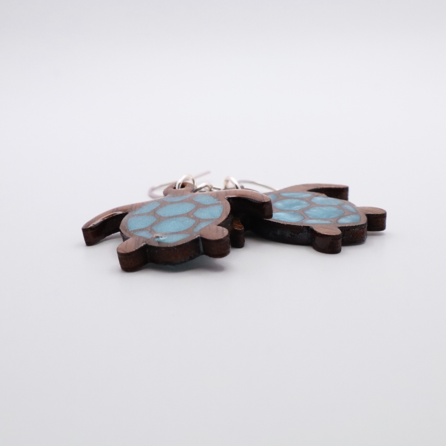 Turtle-shaped earrings with sea glass blue shell design on a white background