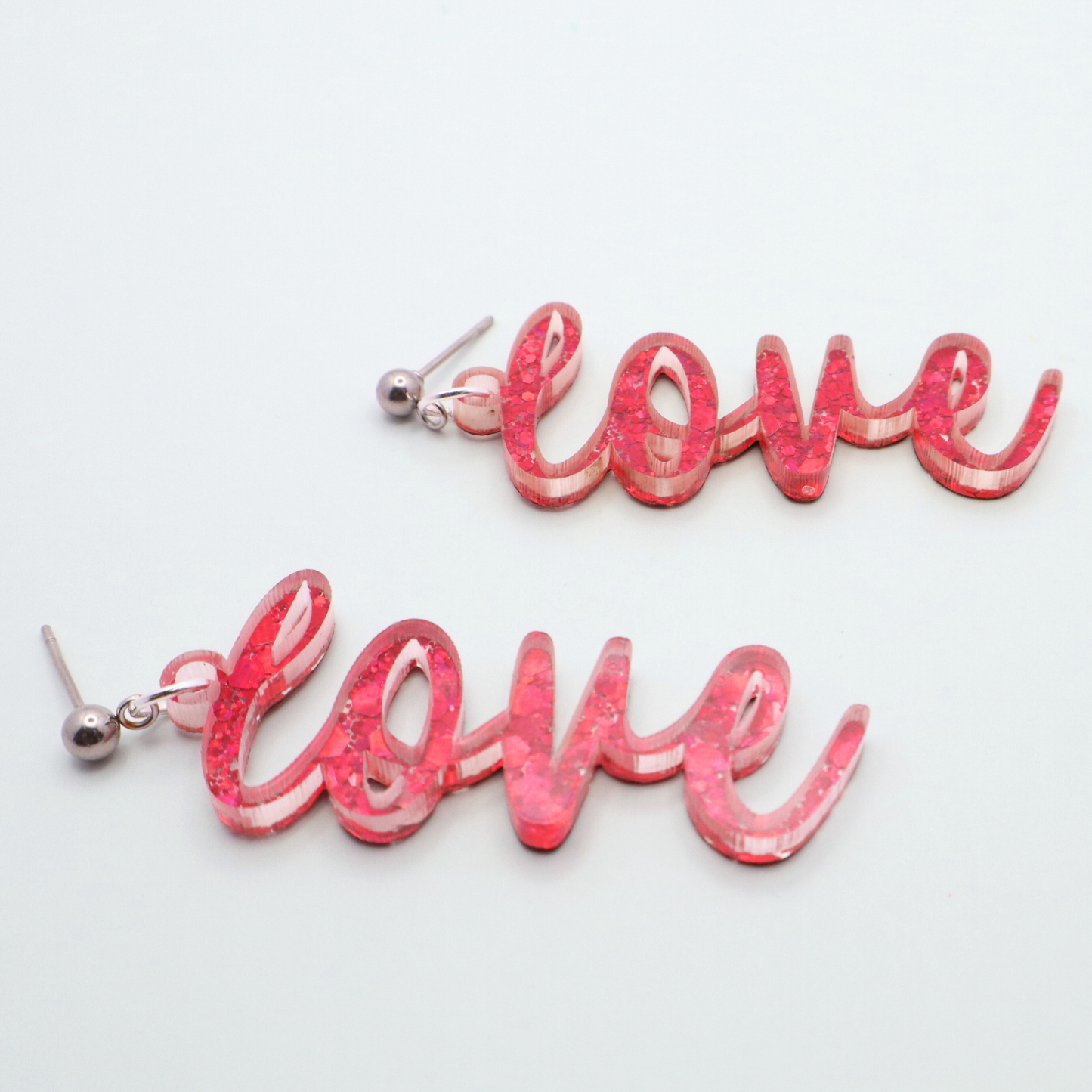 Pink 'love' earrings on a light gray background