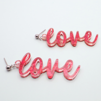 Pink 'love' earrings on a light gray background