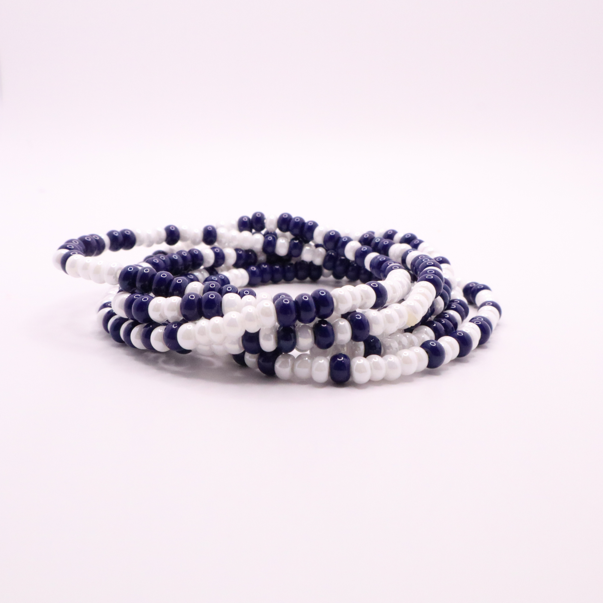Set of six navy blue and white seed bead stretch bracelets featuring random navy blue and white seed beads on a white background
