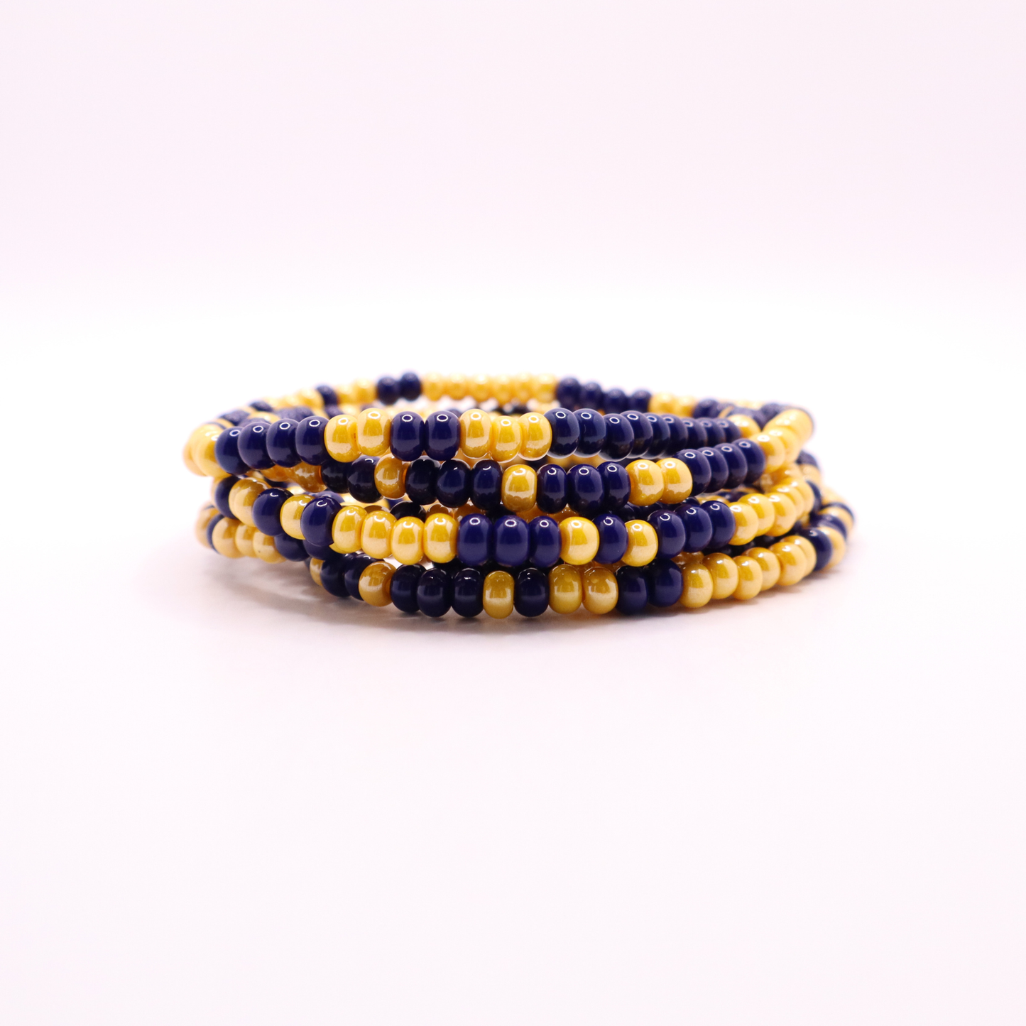 Set of six navy blue and gold seed bead stretch bracelets featuring random red and white seed beads on a white background