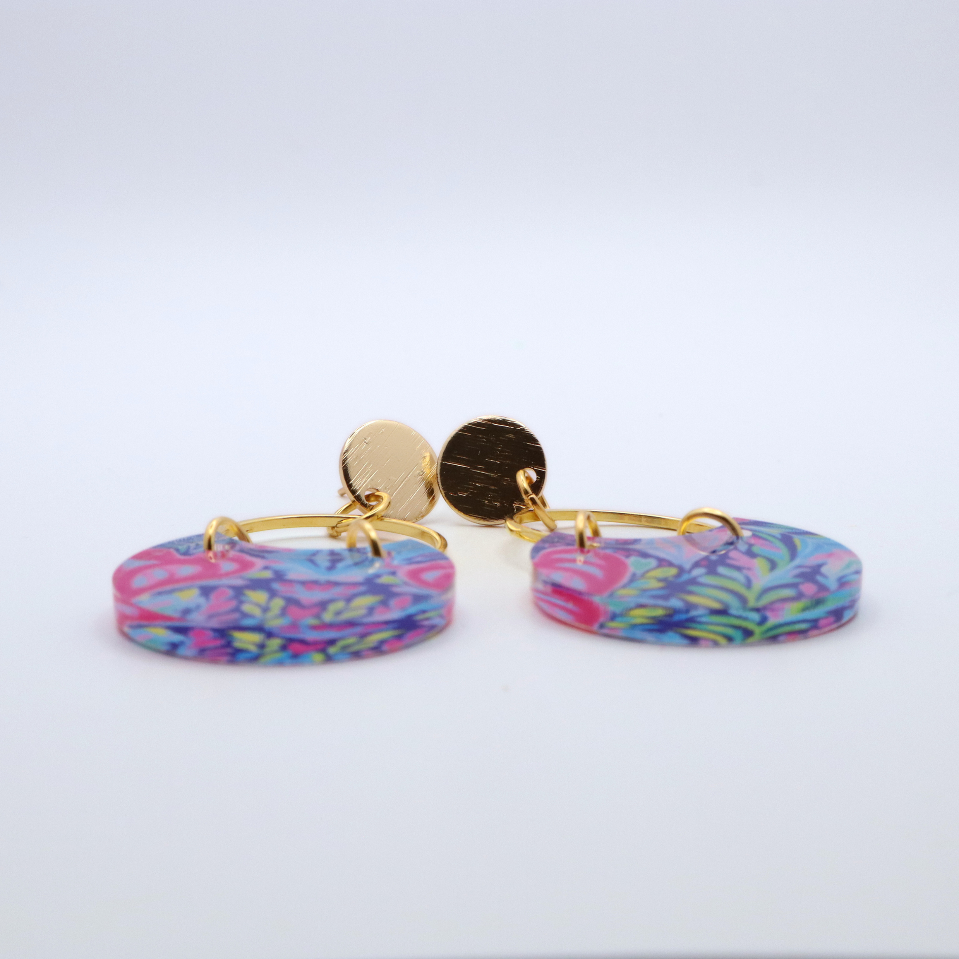 Side profile of acrylic dangle earrings showing thickness and glossy finish with colorful floral pattern and gold hoop with 18k gold plated posts