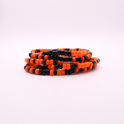 Set of six orange and black seed bead stretch bracelets featuring random orange and black seed beads on a white background