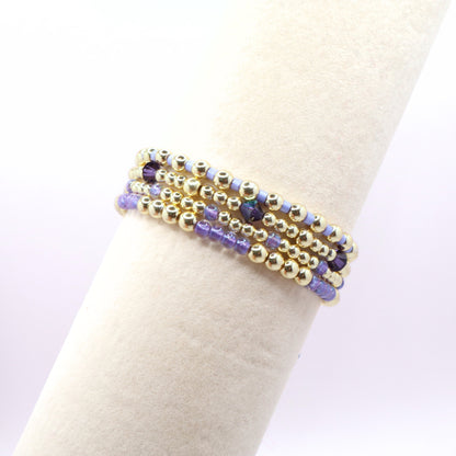 Coastal-inspired lavender and gold stretch bracelet stack shown on a bracelet display stand.