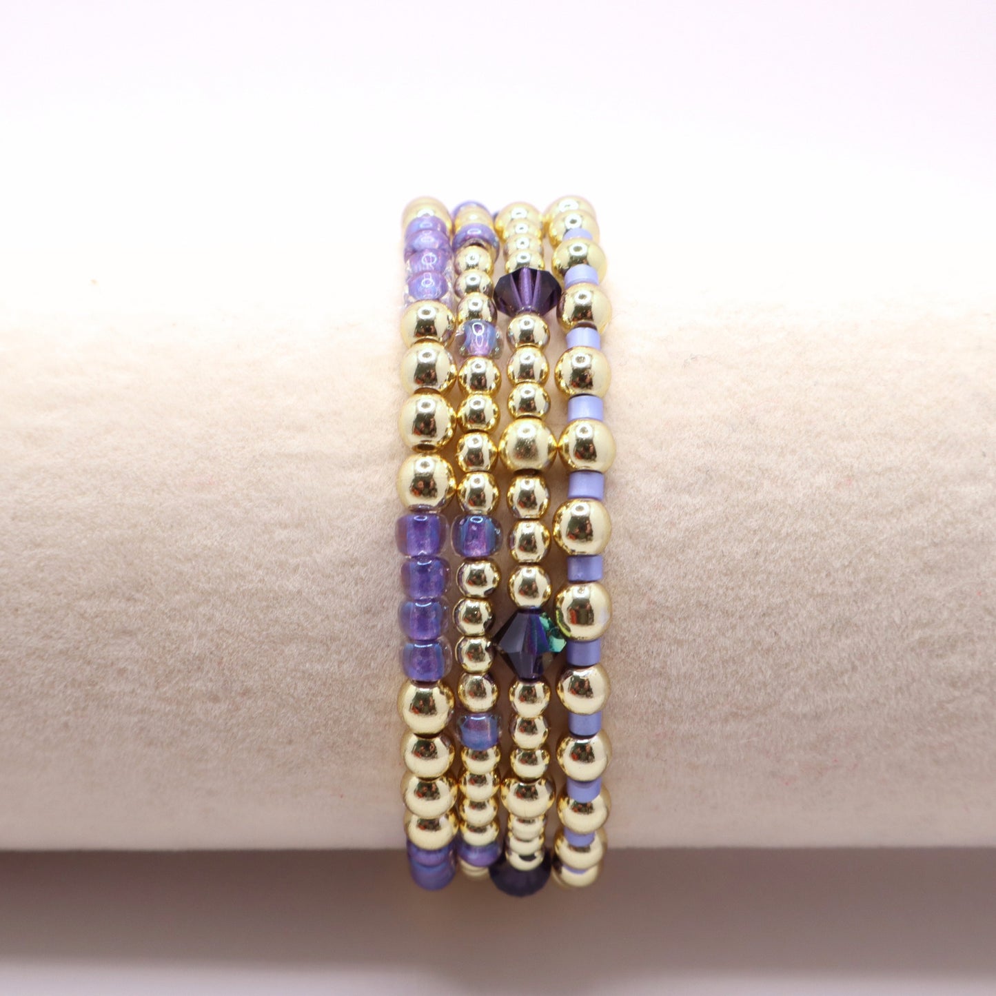 Handmade stretch bracelets in lavender and gold tones styled together as a layered jewelry stack.