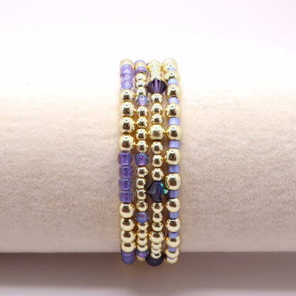 Handmade stretch bracelets in lavender and gold tones styled together as a layered jewelry stack.