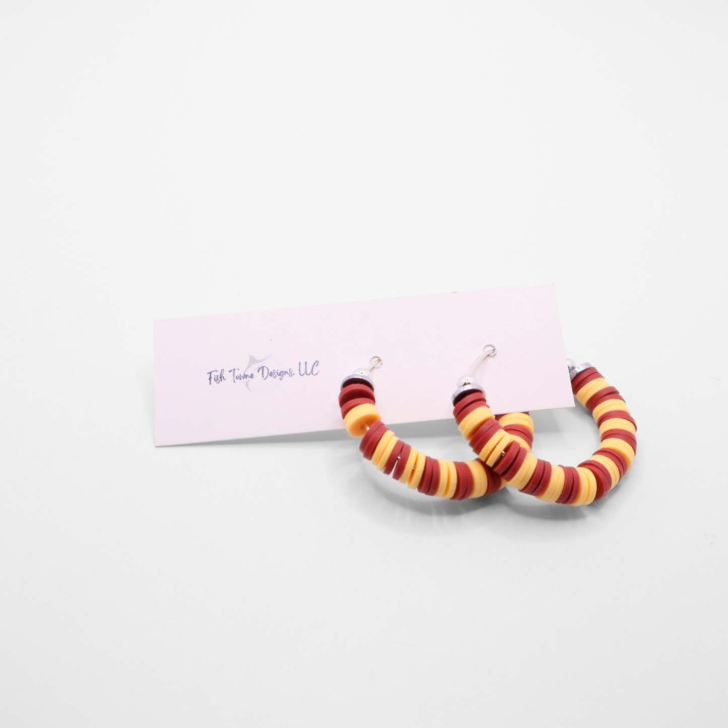 Burgundy and gold heishi bead hoop earrings with gold accents displayed on a branded card against a white background