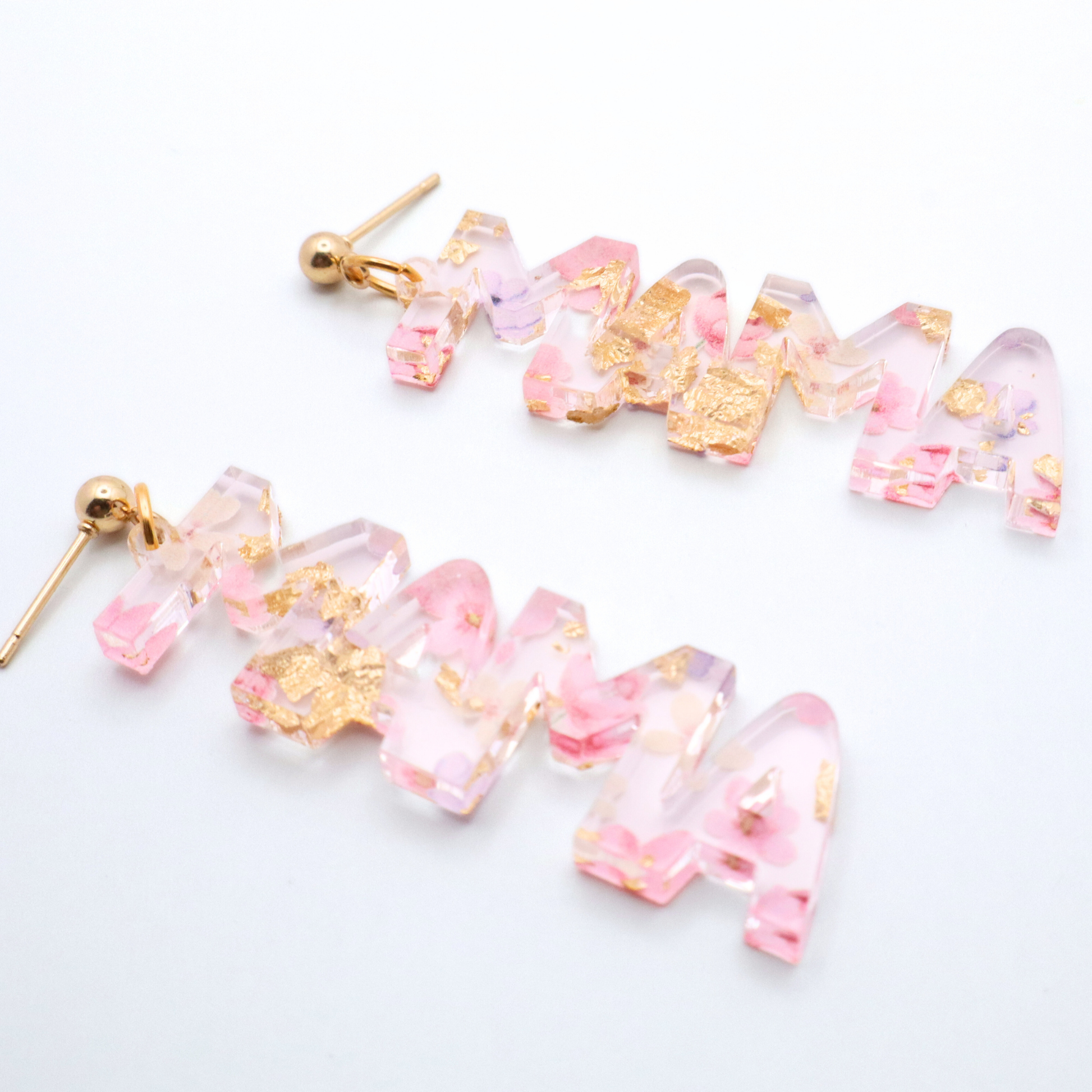 Pair of pink and gold mama earrings on a white background