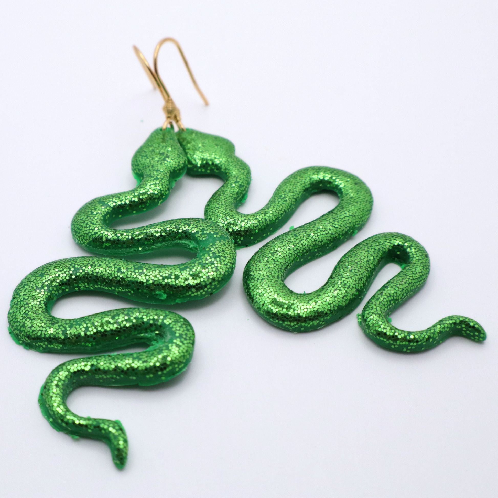 Green glitter snake-shaped earrings on a white background
