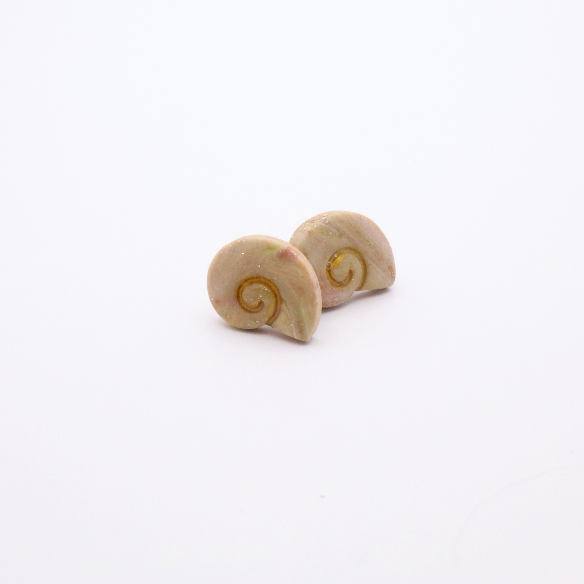 Close-up of marbled resin shell earrings with soft pastel hues and gold leaf flecks