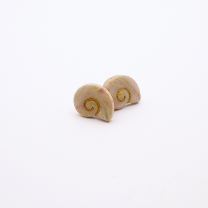 Close-up of marbled resin shell earrings with soft pastel hues and gold leaf flecks