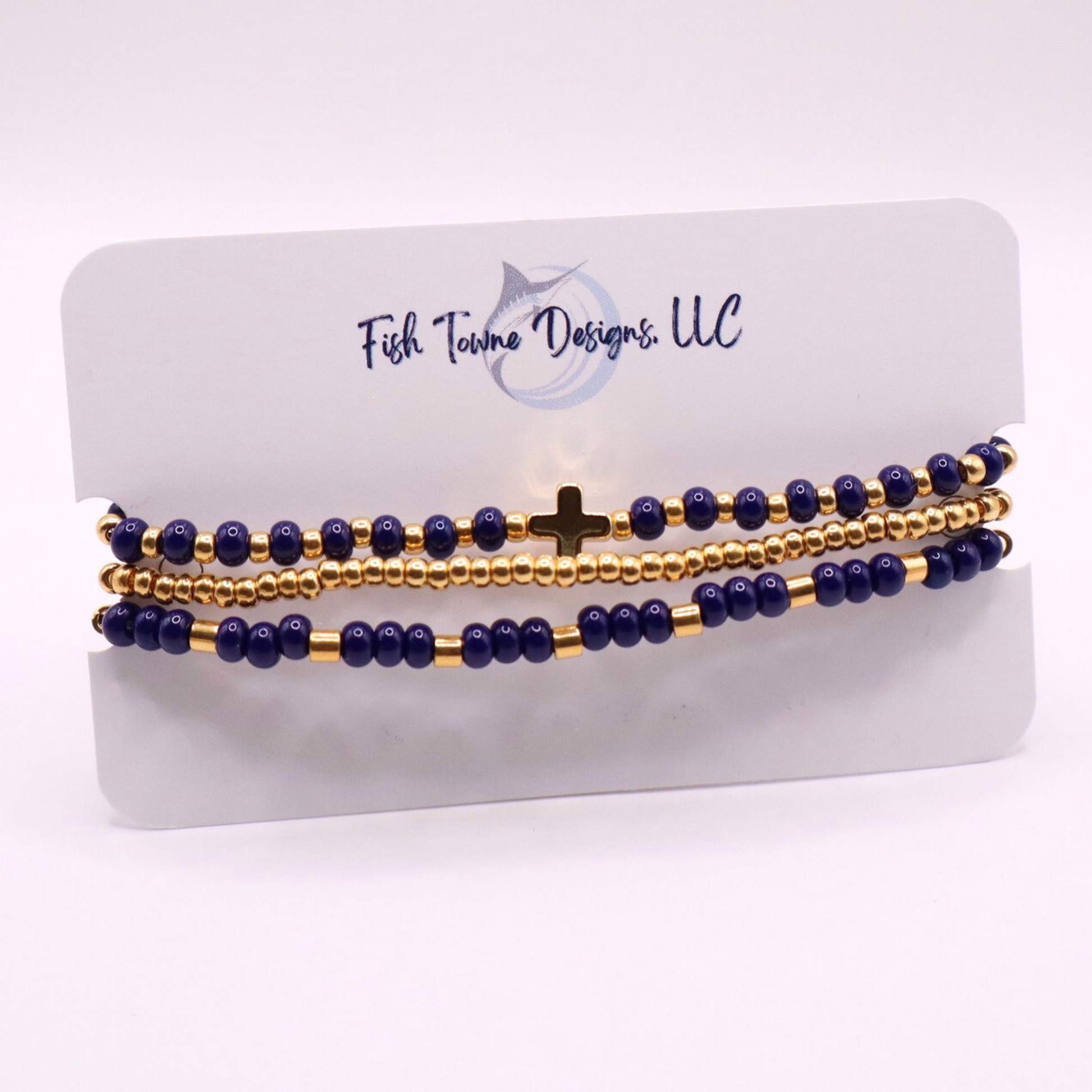 Set of three gold plated beaded bracelets with gold and navy blue beads on a branded card.
