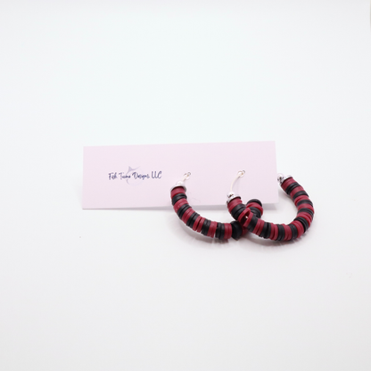 Maroon and black heishi bead hoop earrings with silver accents displayed on a branded card against a white background