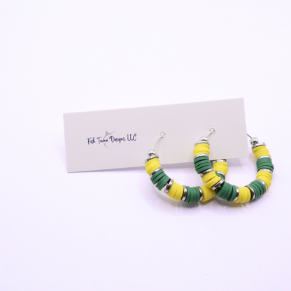 Close-up of green and yellow heishi bead hoop earrings with silver accents on a jewelry stand, highlighting bead detail and pattern