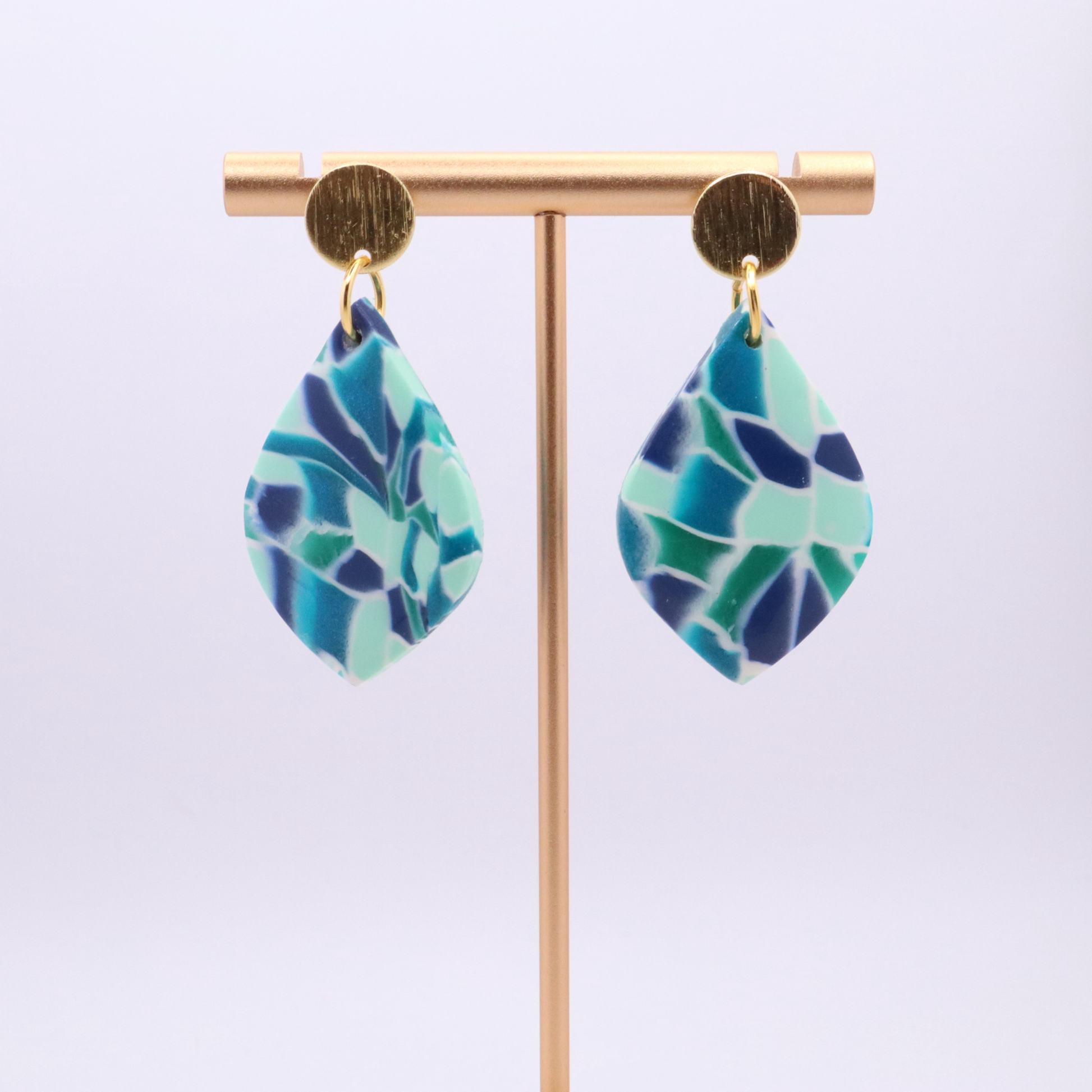 Backside view of polymer clay teardrop earrings showing smooth blue finish and 18k gold plated stud posts with silicone backs