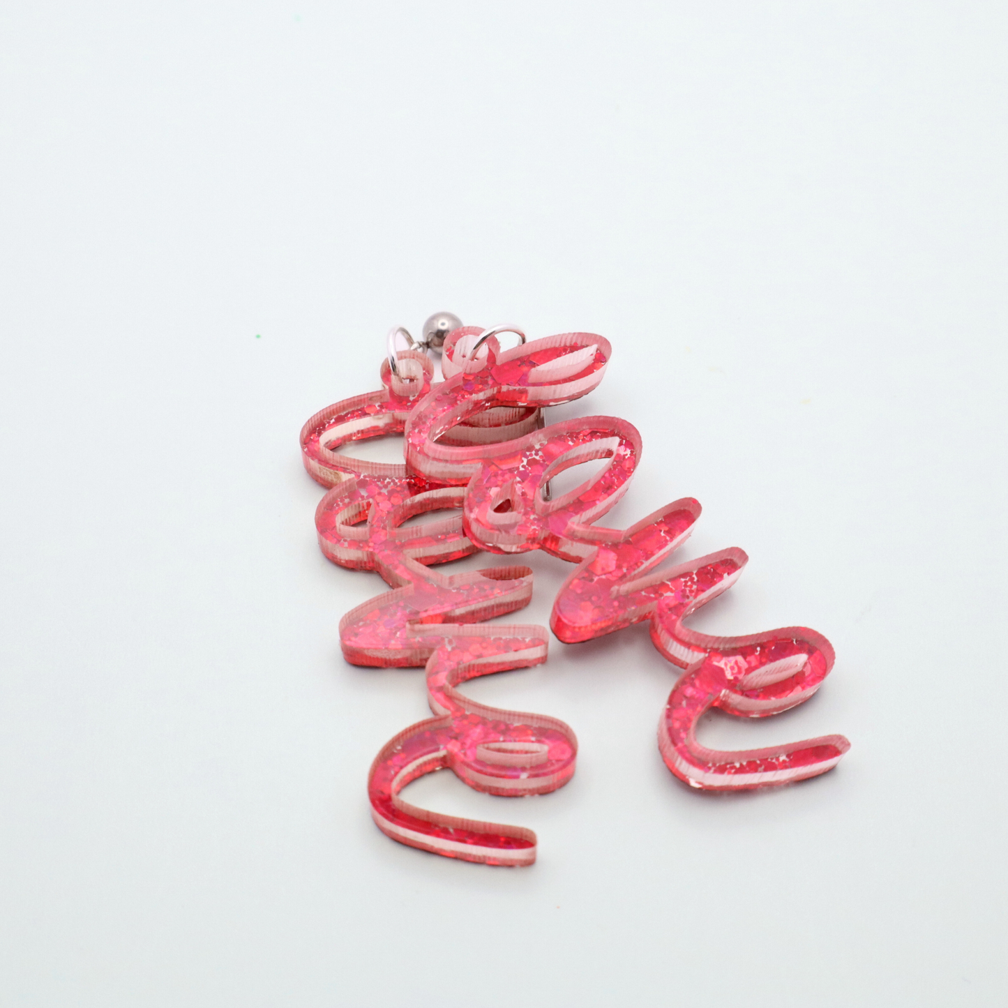 Pink glittery love earrings on a white background