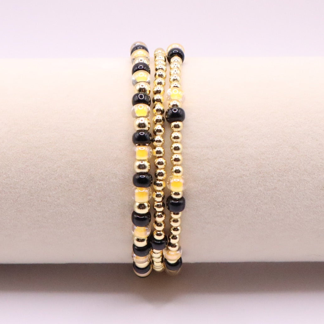 Set of black and gold beaded bracelets on a white surface