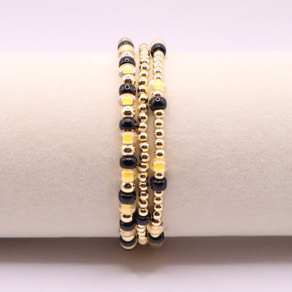 Set of black and gold beaded bracelets on a white surface