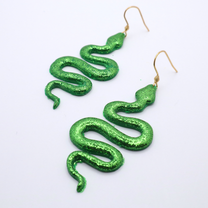 Green glitter snake-shaped earrings on a white background