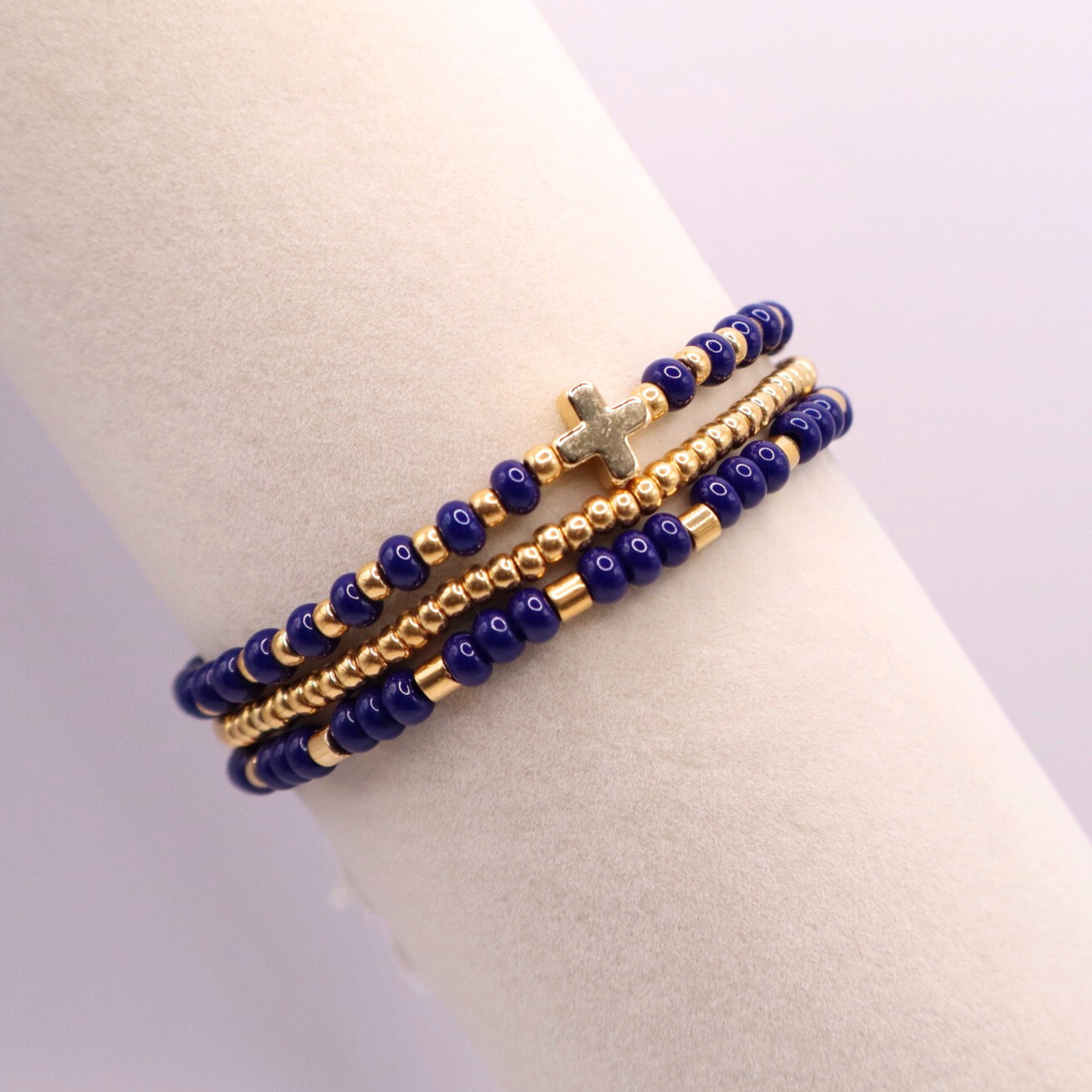 Three gold plated beaded bracelets with blue and gold beads on a bracelet display