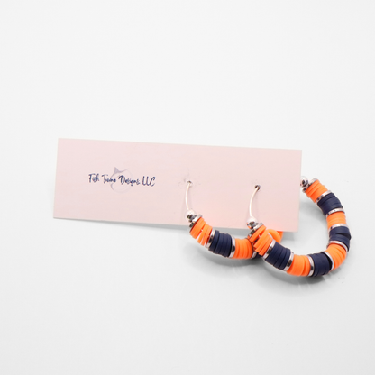 Handmade navy blue and white polymer clay heishi bead hoop earrings with silver spacers shown on a white background with display card