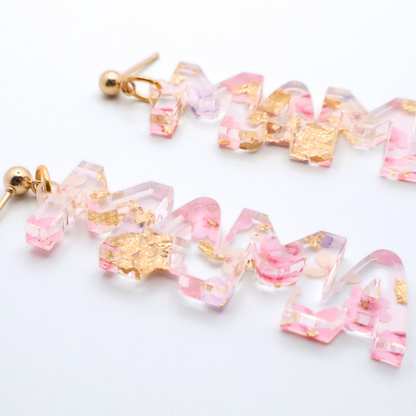 Pair of mama earrings with pink and gold accents on a white background