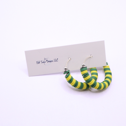 Side angle view of green and yellow heishi bead hoop earrings with silver spacers on a display stand against a white background