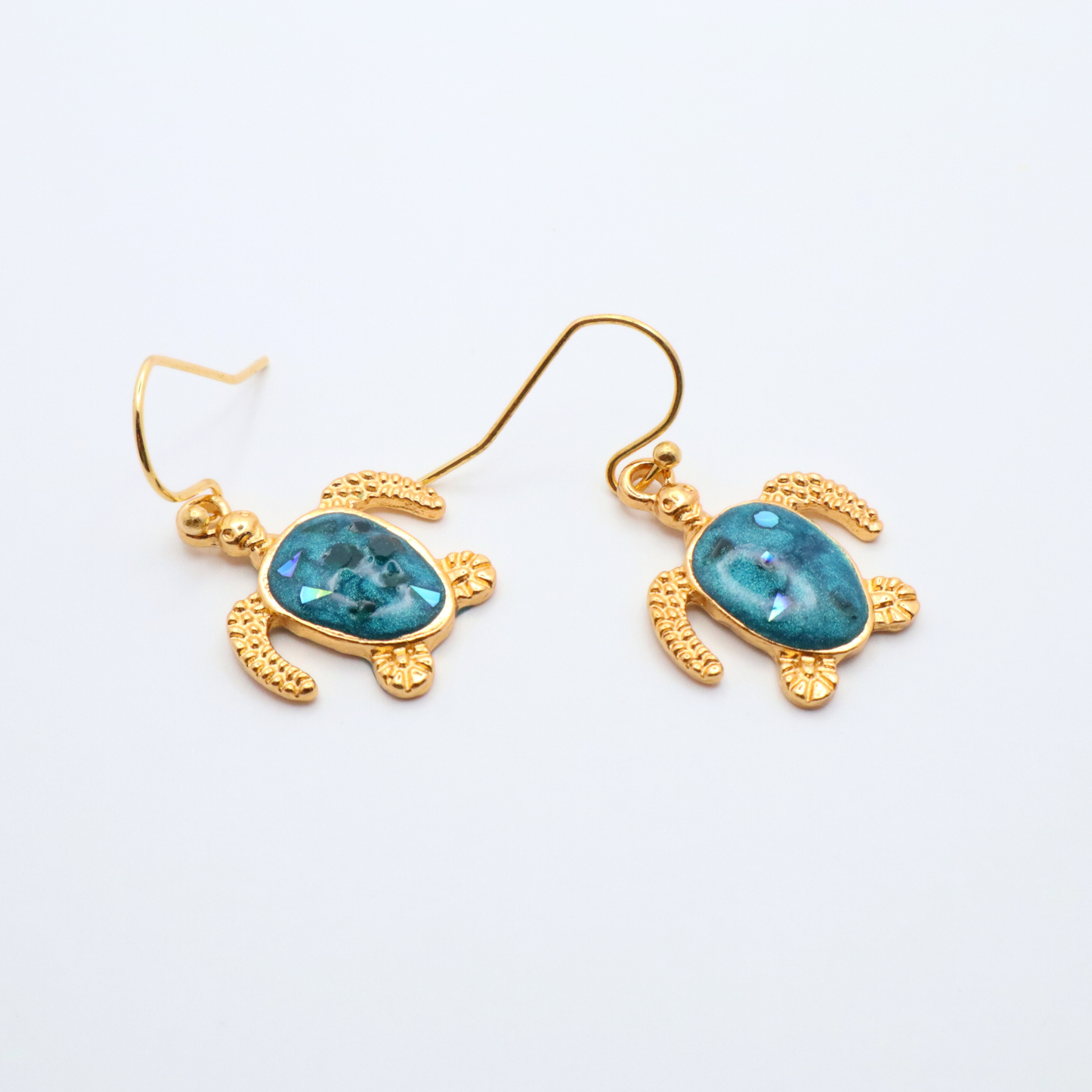Gold turtle-shaped earrings with teal blue resin on a white background