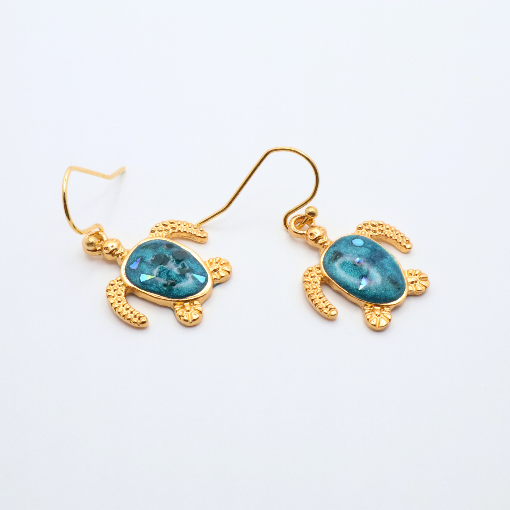 Gold turtle-shaped earrings with teal blue resin on a white background