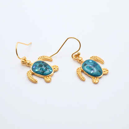 Gold turtle-shaped earrings with teal blue resin on a white background
