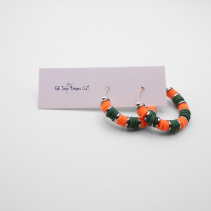 Handmade orange and green polymer clay heishi bead hoop earrings with silver spacers shown on a white background with display card