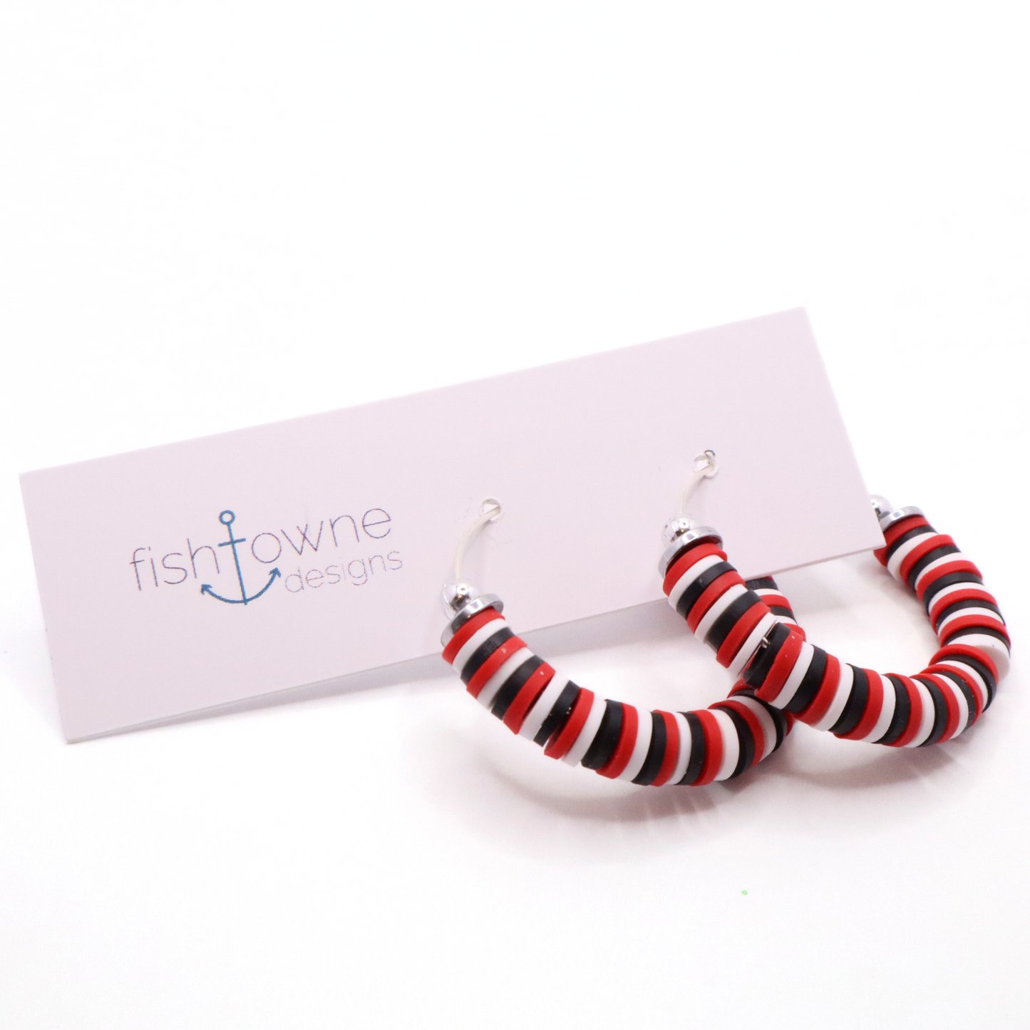 Red, white, and black heishi bead hoop earrings with silver accents displayed on a branded card against a white background