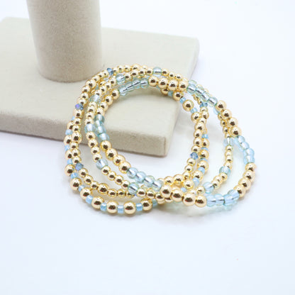 Three coordinating handmade bracelets featuring sky blue and gold bead combinations.