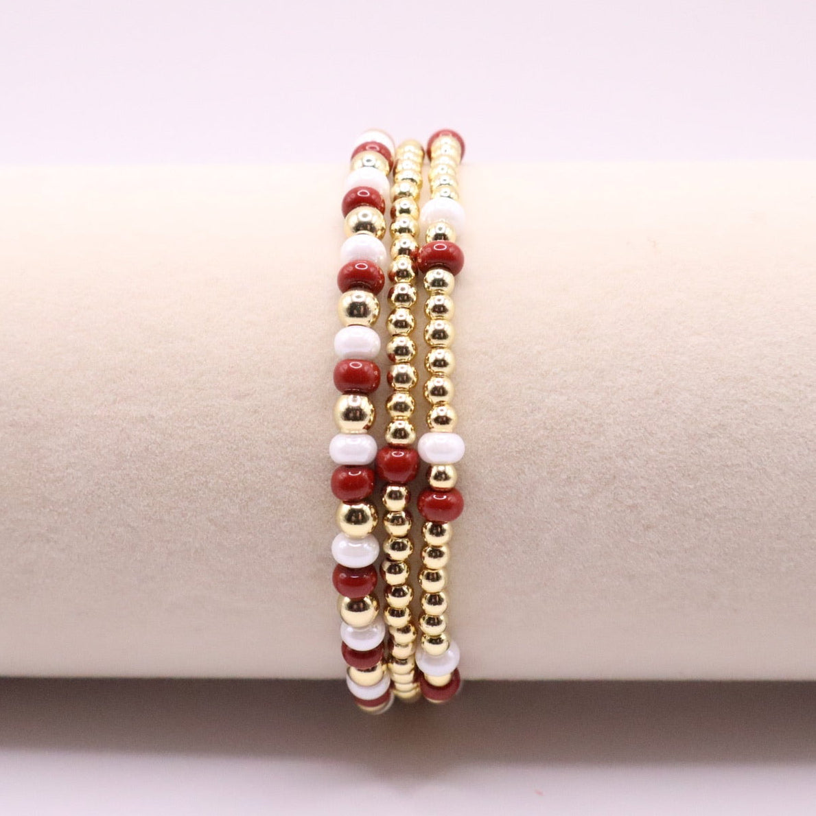 Three crimson, white, and gold displayed on a round bracelet holder