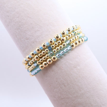 Layered blue and gold bracelet stack displayed on a jewelry stand.