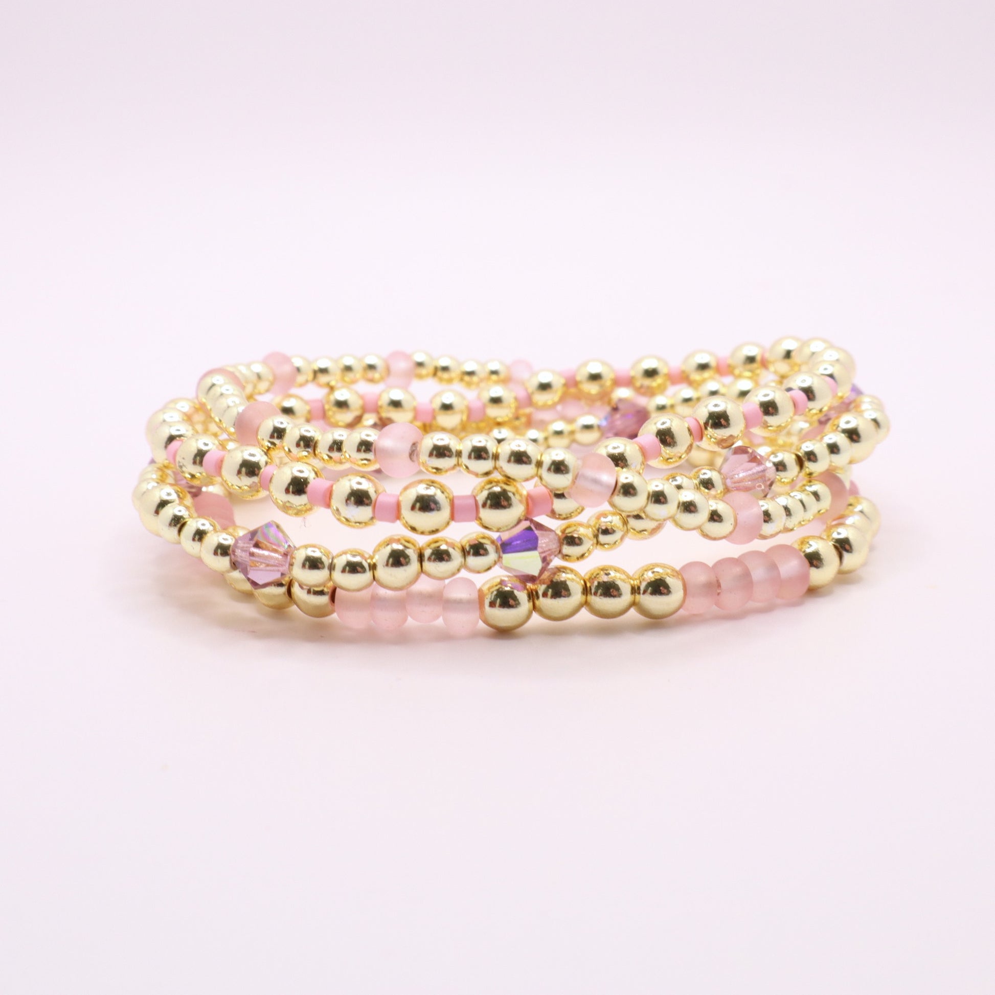 Handmade gold hematite bracelet collection featuring soft pink glass beads.