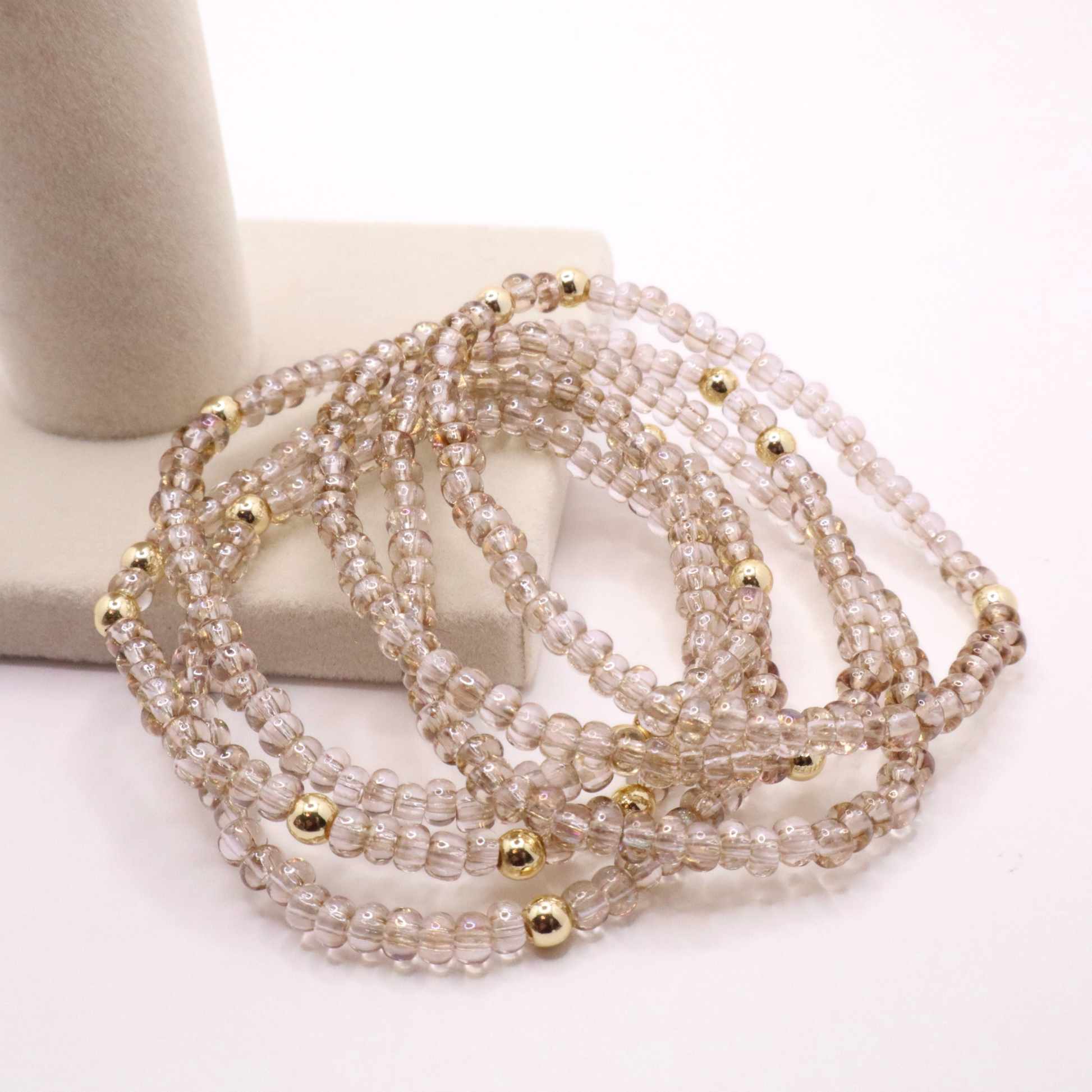 set of six neutral gold tone seed bead bracelets featuring high quality neutral seed beads and golden hematite accent beads.  The stack is displayed on a white background.
