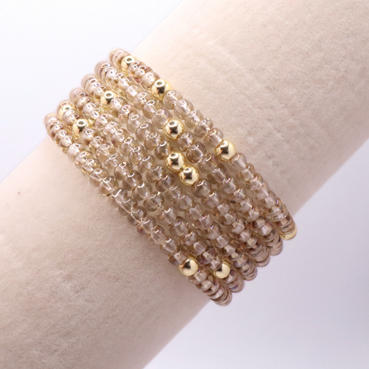 set of six neutral gold tone seed bead bracelets featuring high quality neutral seed beads and golden hematite accent beads.  The stack is displayed on a white background.