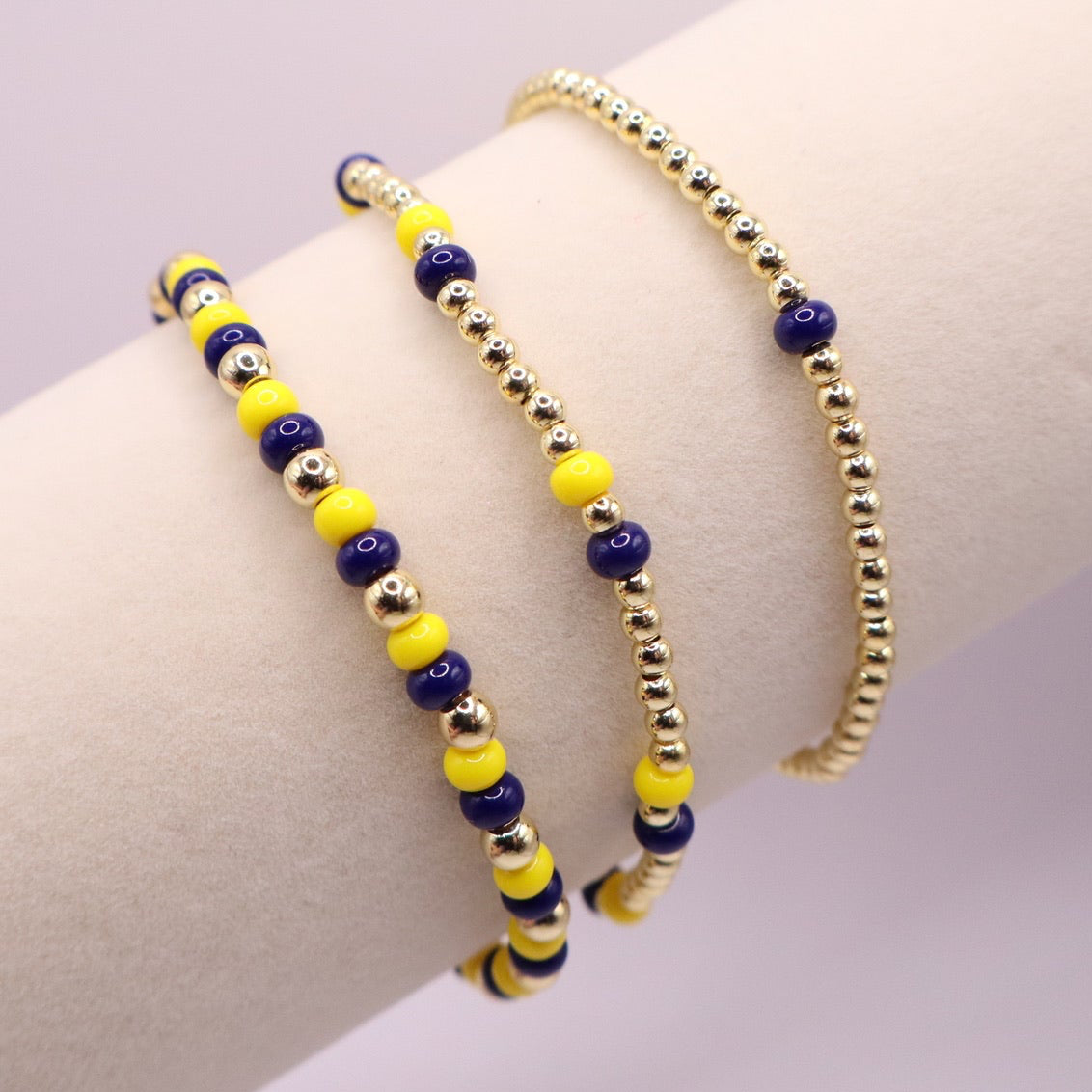 Three beaded bracelets on a wrist against a light background