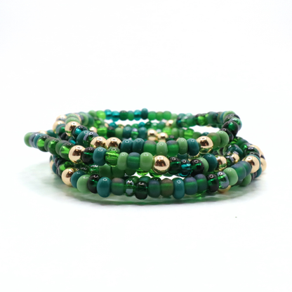Set of six green beaded bracelets with gold accents on a white background