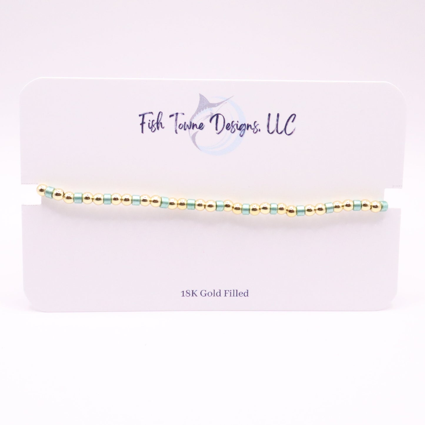 Gold and turquoise beaded bracelet on a white card with 'Fish Towne Designs, LLC' branding.