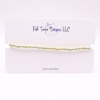 Gold and turquoise beaded bracelet on a white card with 'Fish Towne Designs, LLC' branding.